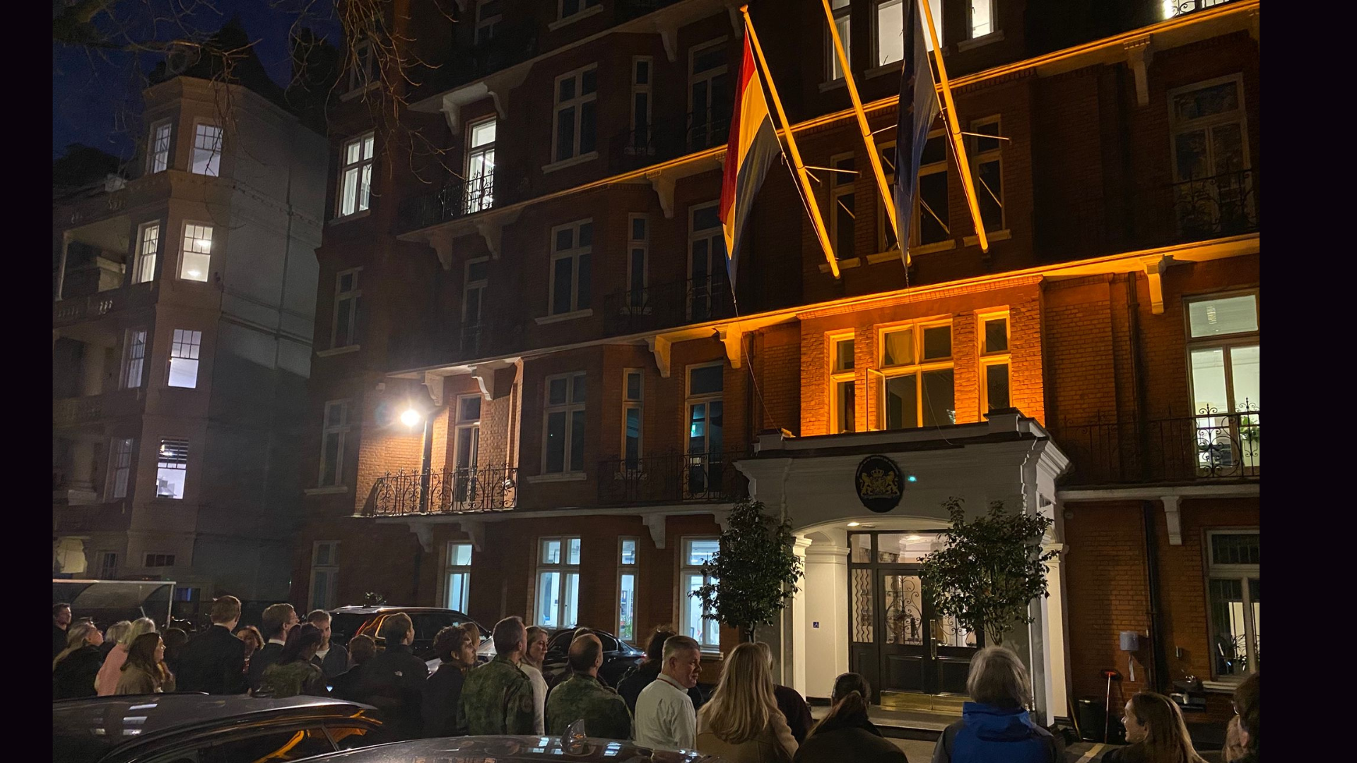 Embassy facade and flag illuminated in orange light. 