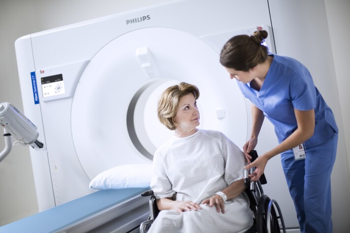 Technician looking at patient laying on IQon Spectral CT bed